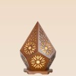 Wooden table lamp with floral cutout design and pentagonal shape emitting warm ambient light