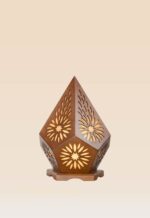 Wooden table lamp with floral cutout design and pentagonal shape emitting warm ambient light