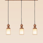 Horizontal triple pendant light with turned wooden tops and frosted square glass – Checkmark Model 57h3 – rustic linear ceiling light for kitchen and dining spaces