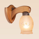 Single-arm wooden wall sconce light with curved bracket and frosted etched glass shade – distributed by Checkmark, crafted by DARKAR Lighting Industries.