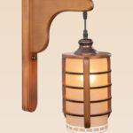 Wooden wall sconce light with amber cylindrical glass shade in a cage design – distributed by Checkmark, crafted by DARKAR Lighting Industries.