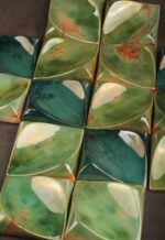 Handcrafted ceramic decorative square tile with green lustre finish reflecting ambient light