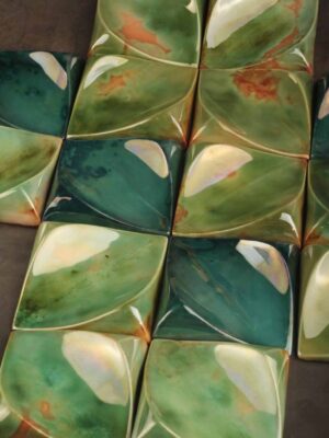 Handcrafted ceramic decorative square tile with green lustre finish reflecting ambient light