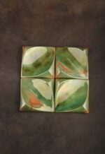Handcrafted ceramic decorative square tile reflecting light across its curved lustre-glazed surface
