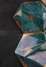 handcrafted ceramic decorative tile with faceted green glaze and amber accents