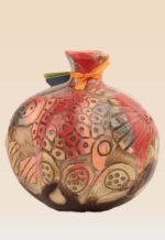 Handmade carved ceramic pomegranate showing relief pattern and artistic glaze