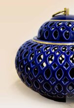 Openwork ceramic lidded jar with glossy glaze and sculptural form close up