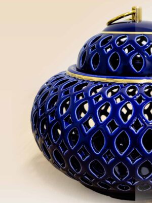 Openwork ceramic lidded jar with glossy glaze and sculptural form close up