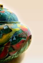Patina glaze ceramic lidded jar with layered color tones and sculptural form close up