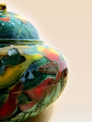 Patina glaze ceramic lidded jar with layered color tones and sculptural form close up