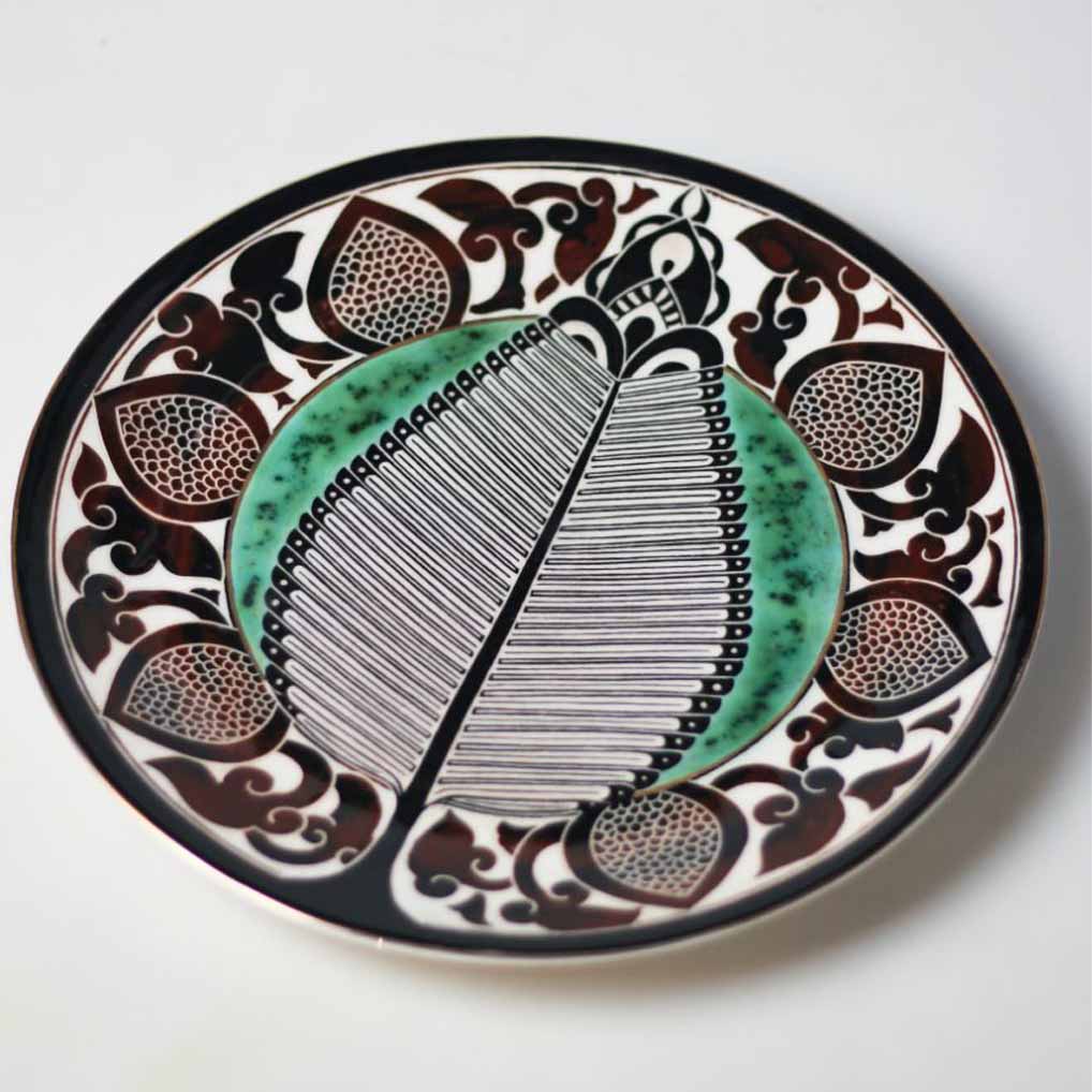 Decorative ceramic dish displayed on a shelf with handmade ceramic art objects